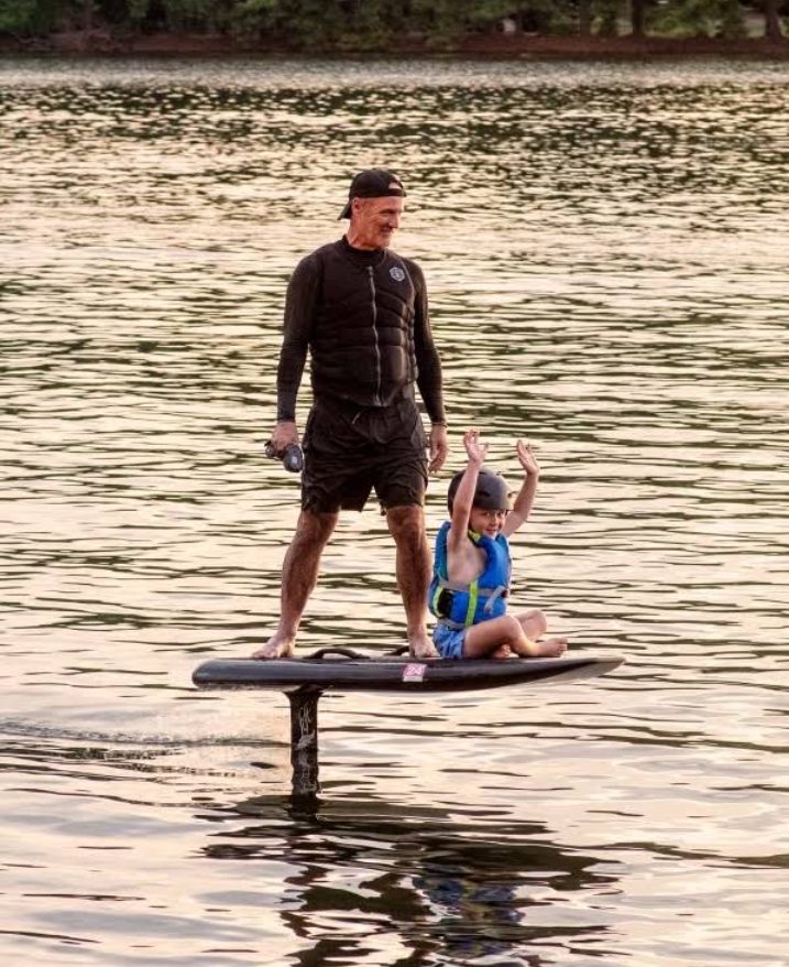 A father and son riding an eFoil together at sunset