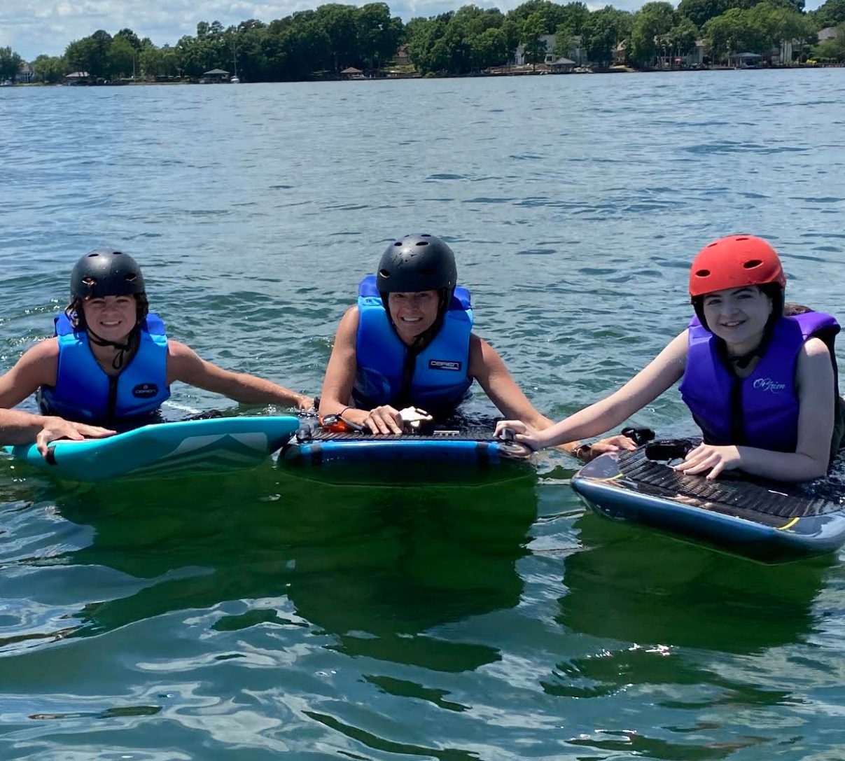 Three riders in helmets and life jackets holding their eFoils during a lesson